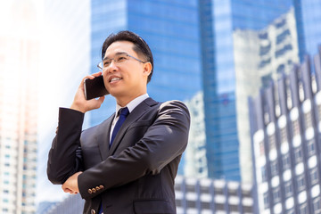 Portrait charming handsome executive man: Attractive businessman or boss is calling his customer for asking deal of business. Handsome middle aged man get satisfied agreement of deal. city background