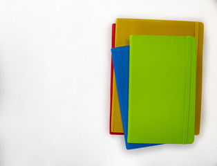 A stack of bright colorful notebooks on an isolated white background with room for text and other objects 