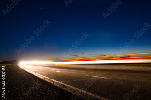 Plakat The asphalt road in the countryside with the light passing through it at the spe