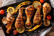 Delicious food: grilled chicken drumstick legs with vegetables in a grill pan close-up on a table. horizontal top view, rustic