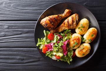 Wall Mural - Delicious food: grilled chicken drumsticks with new potatoes and fresh salad closeup on a plate. horizontal top view