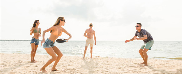 Group of friends playing at the beach on summer holidays