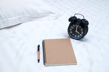 Wall Mural - Diary or notebook and vintage alarm clock on bed in bedroom at home or hotel..