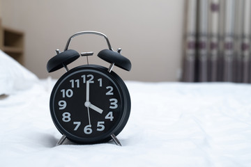 Vintage alarm clock on the bed in bedroom at home, wake up or bed time concept.