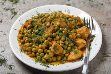 Chiken stew with peas, carrot and tomato sauce on plate with fork