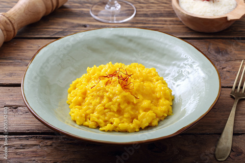 Fotografía risotto allo zafferano tradizionale italiano su sfondo tavolo di cucina rustico