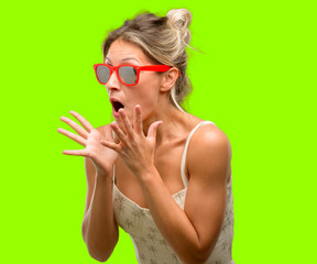 Wall Mural - Young beautiful woman wearing red sunglasses stressful keeping hands on head, terrified in panic, shouting