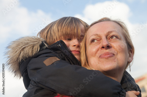 Fotografie, Obraz Happy and proud mother carries her little son in the back