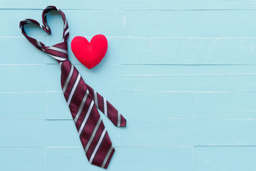 Happy fathers day concept. Red tie in heart shape and handmade red heart on bright blue pastel wooden table background.