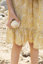 Girl Holding A Shell With A Flower Printed Yellow Skirt