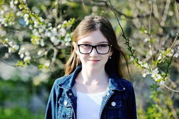 Adorable kid girl in blooming apple garden on beautiful spring day