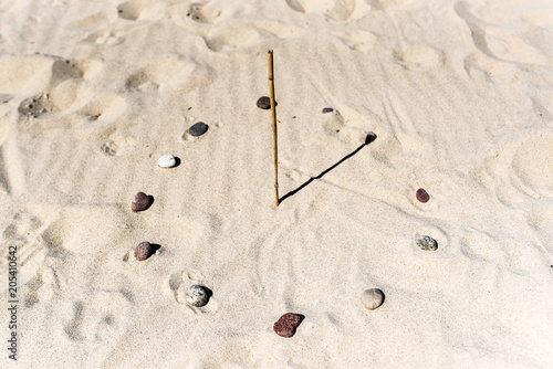 Sundial on the beach made of a stick and stones.Sundial on the beach made of a stick and stones.