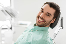 Medicine, Dentistry And Healthcare Concept - Happy Smiling Male Patient On Chair At Dental Clinic
