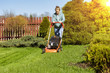 teenage girl working in garden, mowing grass with lawn-mower
