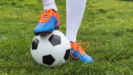 Wall Mural - Football player and ball on a grass close-up