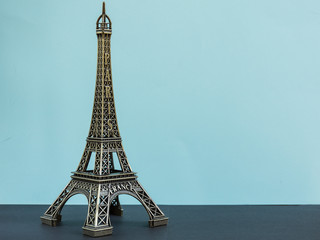 toy eiffel tower on the pastel blue background. copy space. symbol of france.