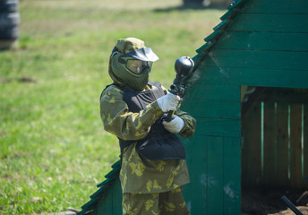 Wall Mural - Boy in camouflage form with gun on the field. Children play paintball on the field. Sport, active lifestyle for kids