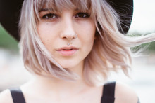 Close Up Portrait Of Beautiful Hipster Girl With Stylish Blonde Hair, Piercing. Woman Wearing Black Hat And Dress