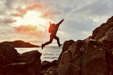 jumping man hiker over a gap between two rocks