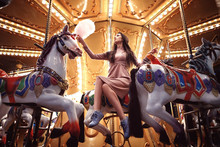 Young Beauty Model Woman Posing With Old Horse Carousel In Summer Park With Magic Lights
