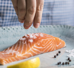 Wall Mural - A person seasoning a fillet of salmon food photography recipe idea