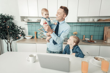 Wall Mural - Lets play. Happy man keeping smile on his face and turning head while looking at his baby