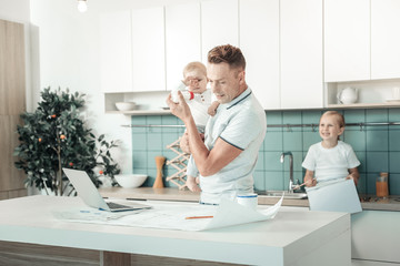 Wall Mural - Checking project. Attentive man standing near table and bowing head while looking at his sketch