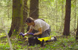 Woman scientist ecologist in the forest taking samples of the moss with tweezers