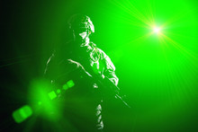 US Marine Raider In Combat Uniform With Hidden Face, Armed With Assault Carbine Low Key, High Contract Studio Shot On Black Background In Blinding Light. Equipped Army Soldier Standing In Darkness