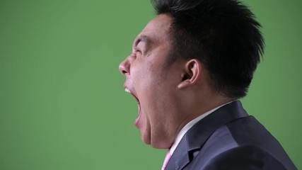 Wall Mural - Young handsome overweight Asian businessman against green background