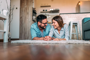 Young couple lying on a floor at home.