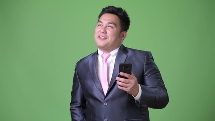 Wall Mural - Young handsome overweight Asian businessman against green background