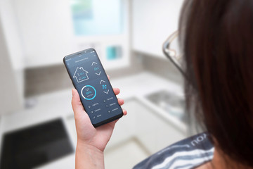 Aufkleber - Woman use smart home control app on modern mobile phone. Home interior in background.