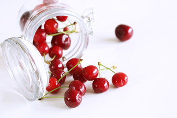 Wall Mural - Glass container filled with juicy fresh cherries on white background. Fresh mandarins fruit for healthy life and detox snacks. Picture design for foods background. Top view. Empty space for your text.