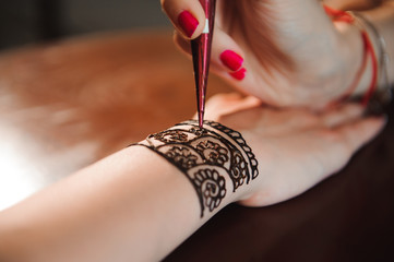 Sticker - Artist applying henna tattoo on women hands. Mehndi is traditional Indian decorative art. Close-up