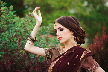 Wall Mural - Portrait of beautiful indian girl. Young hindu woman model with tatoo mehndi and kundan jewelry. Traditional Indian costume saree.