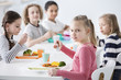 © Photographee.eu - Girl eating vegetables with friends in the canteen during break at school