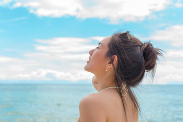 Beautiful young woman in sexy bikini standing at sea beach