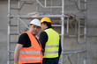 © cineberg - Two happy civil engineers wearing protective vests and helmets at work on construction site