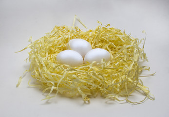 three white eggs lie in a straw nest