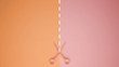 Scissors with cut lines on pastel orange and pink colored background with copy space, template mockup concept idea