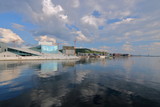 Fototapeta  - Widok budynku opery w Oslo, Norwegia, z przeciwnego brzegu zatoki morza, promenady z nowymi budynkami na brzegu, słonecznie, malownicze chmury na niebie