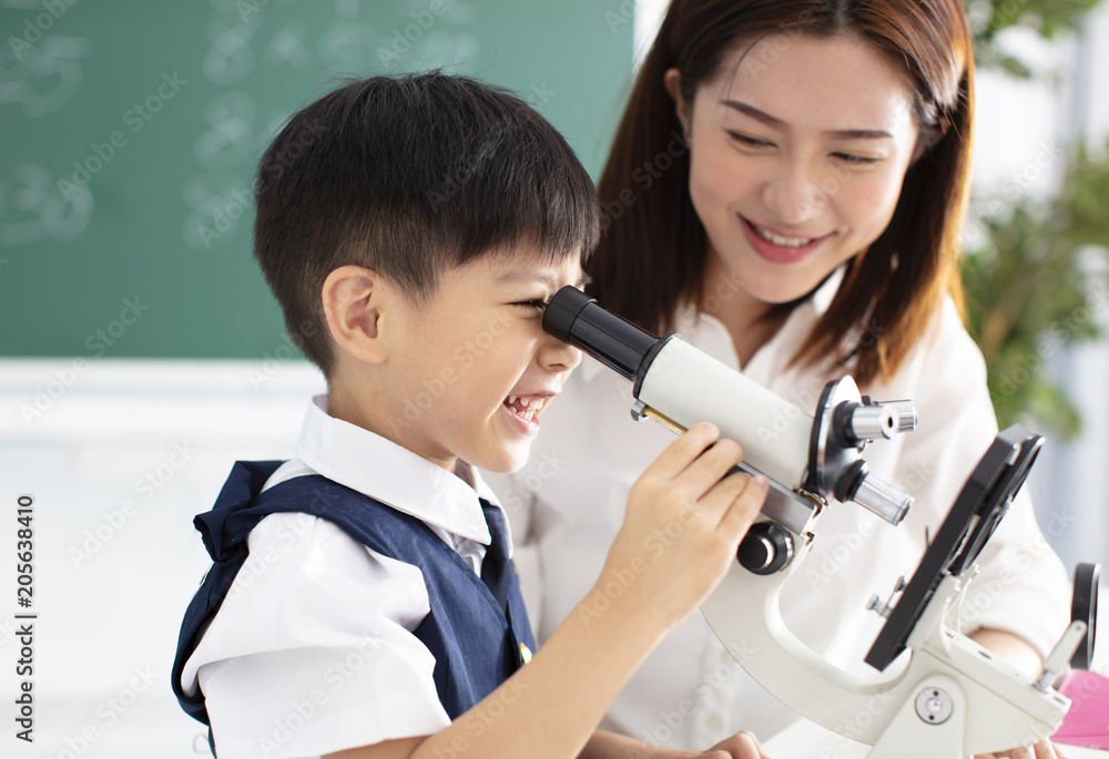 teacher helps child to conduct experiment with microscope Stock Photo ...