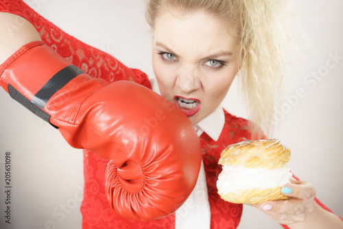 Fotografie, Tablou Woman fighting off bad food, boxing cream puff cake