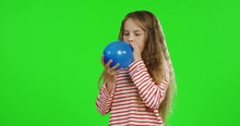 Cute Blond Teenage Little Girl With A Long Hair Inflating A Blue Balloon On The Chroma Key Background. Green Screen