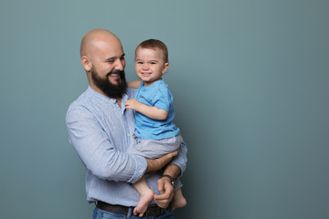 Portrait of dad and his little son on color background