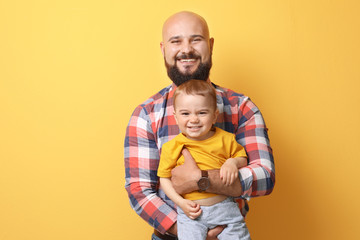 Portrait of dad and his little son on color background