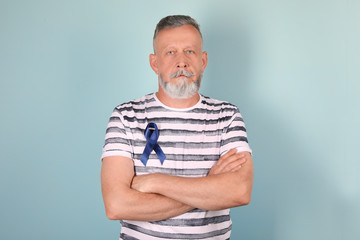 Sticker - Mature man with blue ribbon on color background. Urological cancer awareness