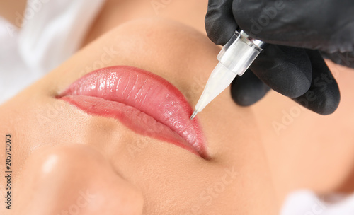 Young woman getting permanent makeup on lips in beautician salon, closeup Poster Mural XXL