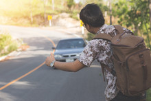 young men with backpack hitchhiking hand sign on the road,stop concept,